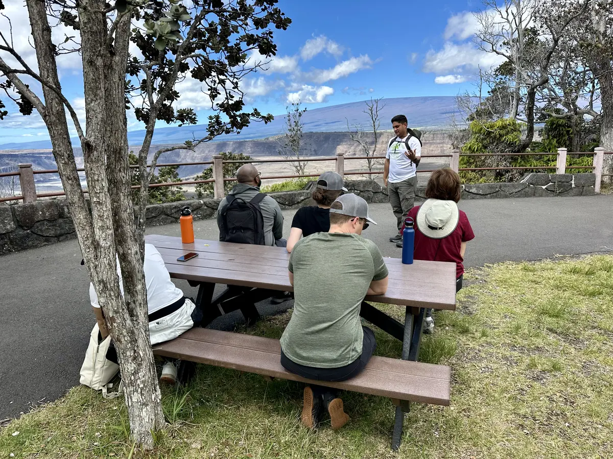 Team members listening during an outdoor conversation in a volcanic landscape