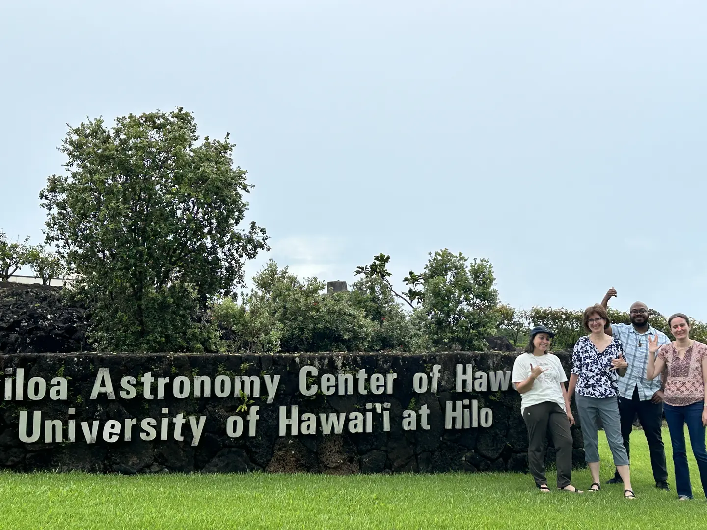 Members of the visiting team gathered beside the ʻImiloa Astronomy Center of Hawaiʻi sign