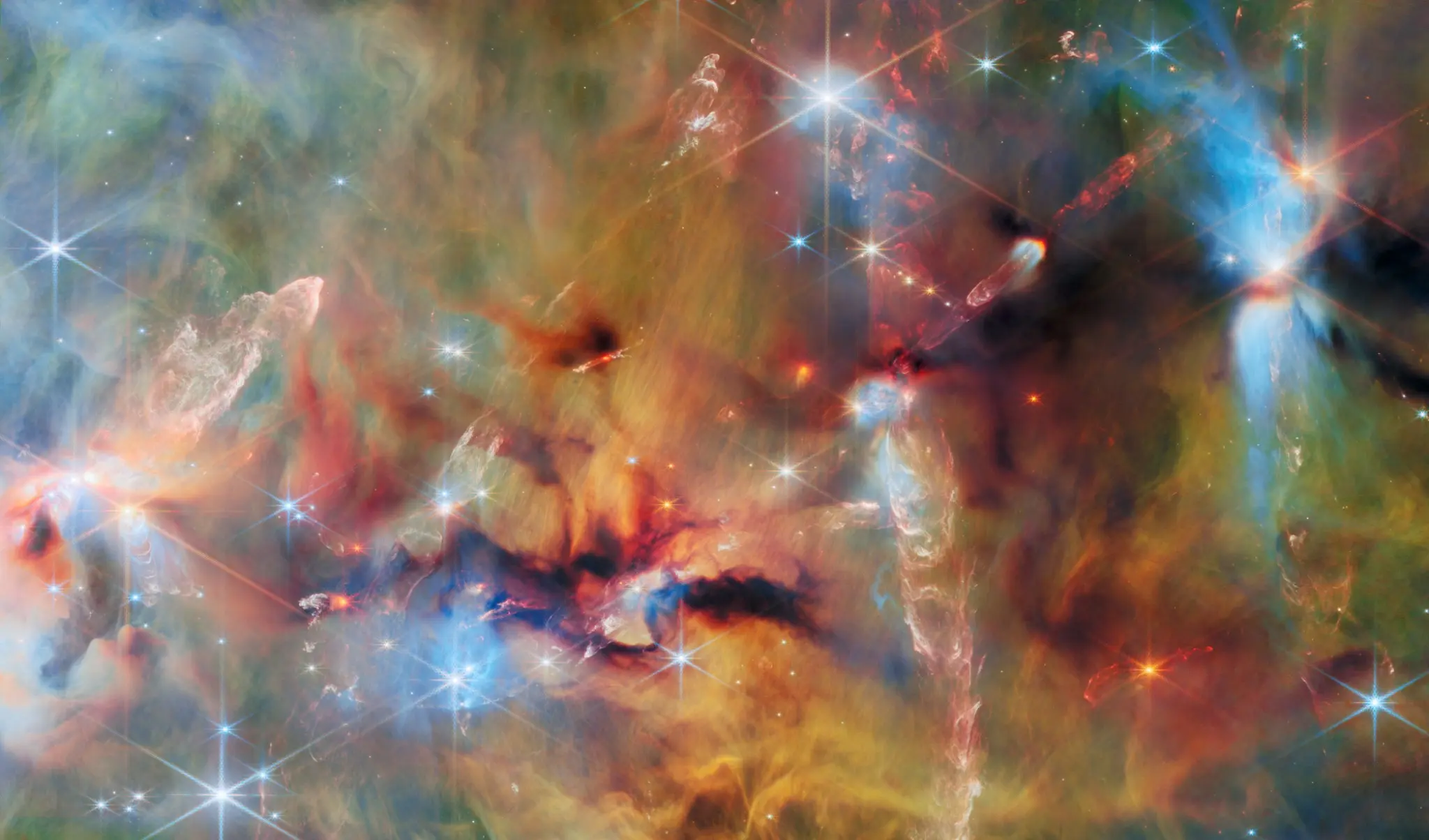 Webb view inside an Orion molecular cloud, with young stars shining through layered blue, green, yellow, and dark brown gas and dust